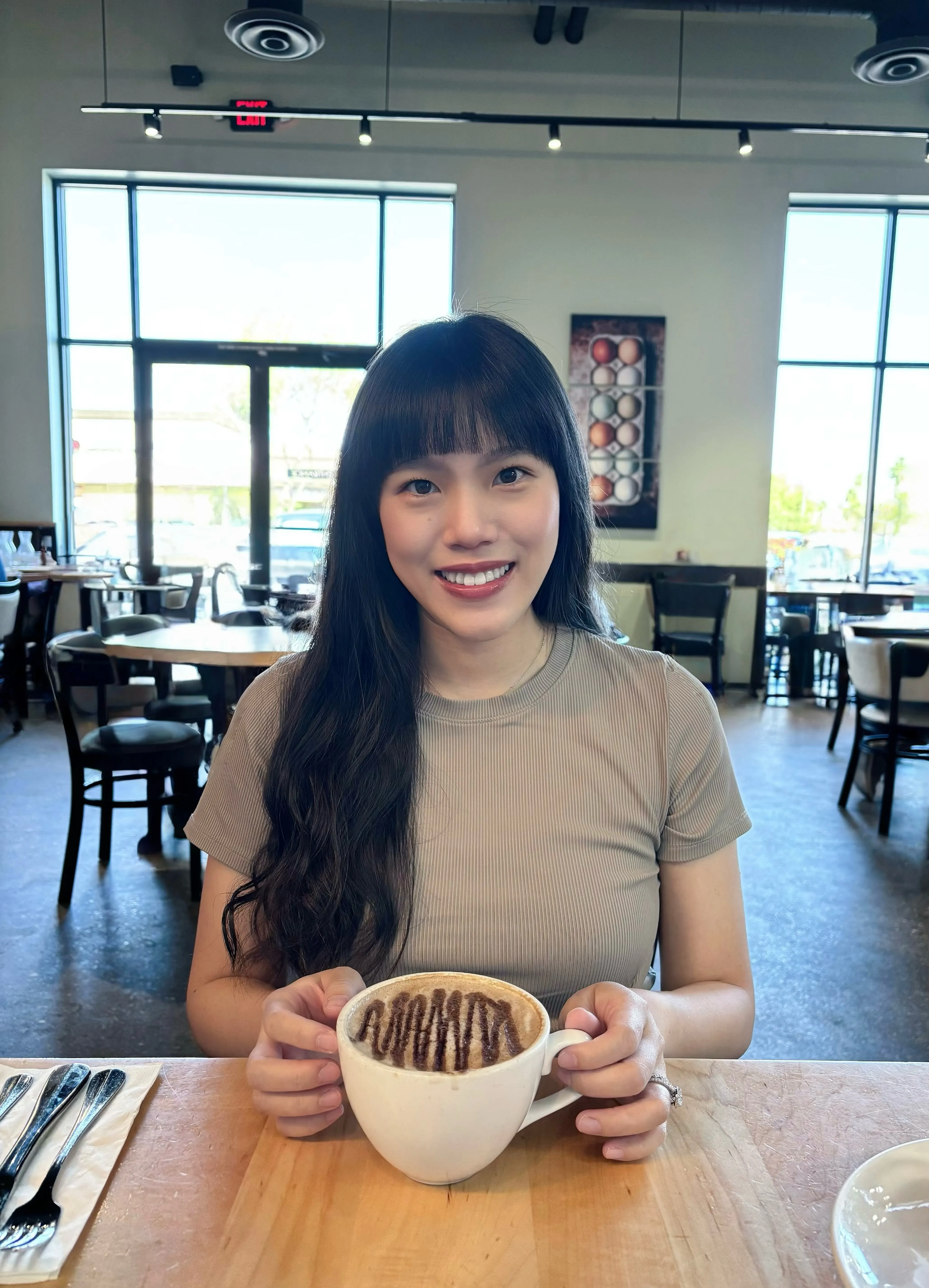 Angela Liu, smiling at a cafe table with a latte